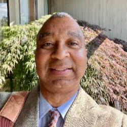 A headshot of an artist wearing a suit and tie